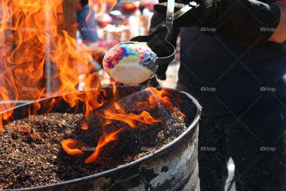 YOU'RE FIRED!. Artisan firing a clay pot to bein out colors in copper paint