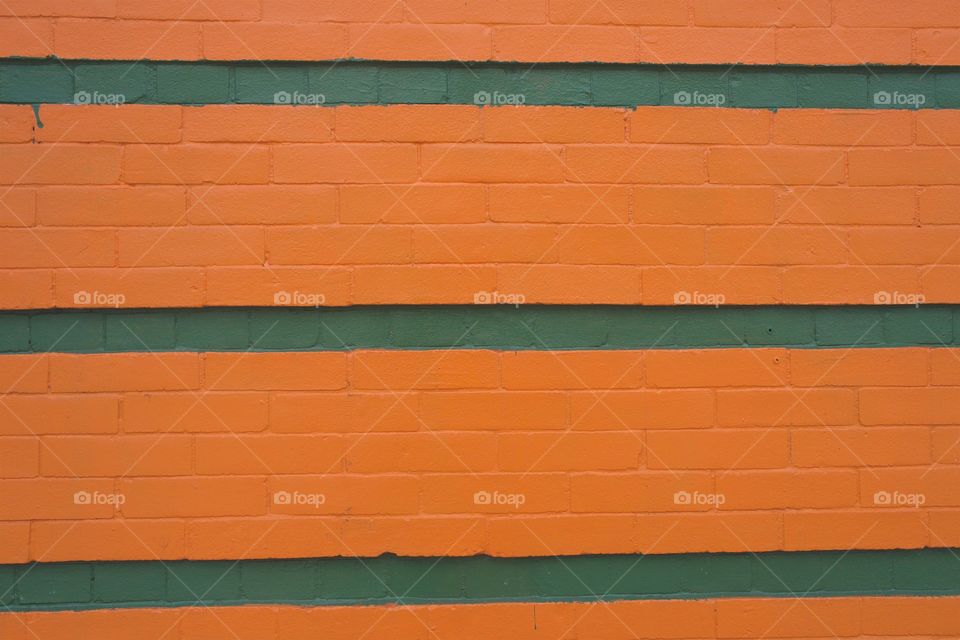 A closeup of an orange and green brick wall of a commercial building in Brooklyn, New York City.
