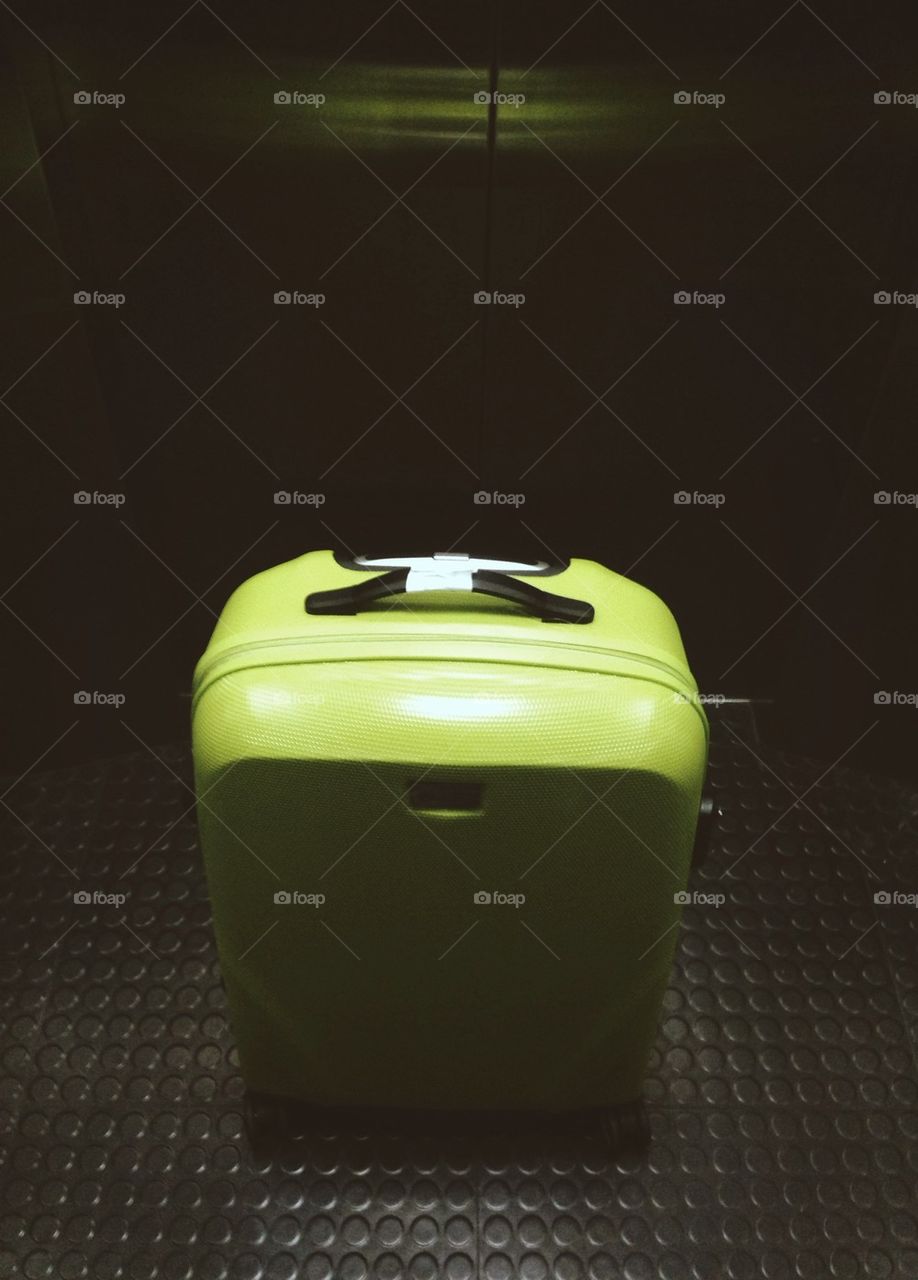Green luggage standing in elevator