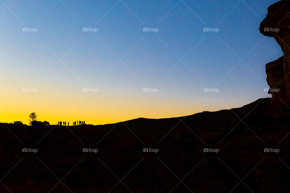 Sunset over the mountains with a group of friends on the horizon. Blue and orange colors.