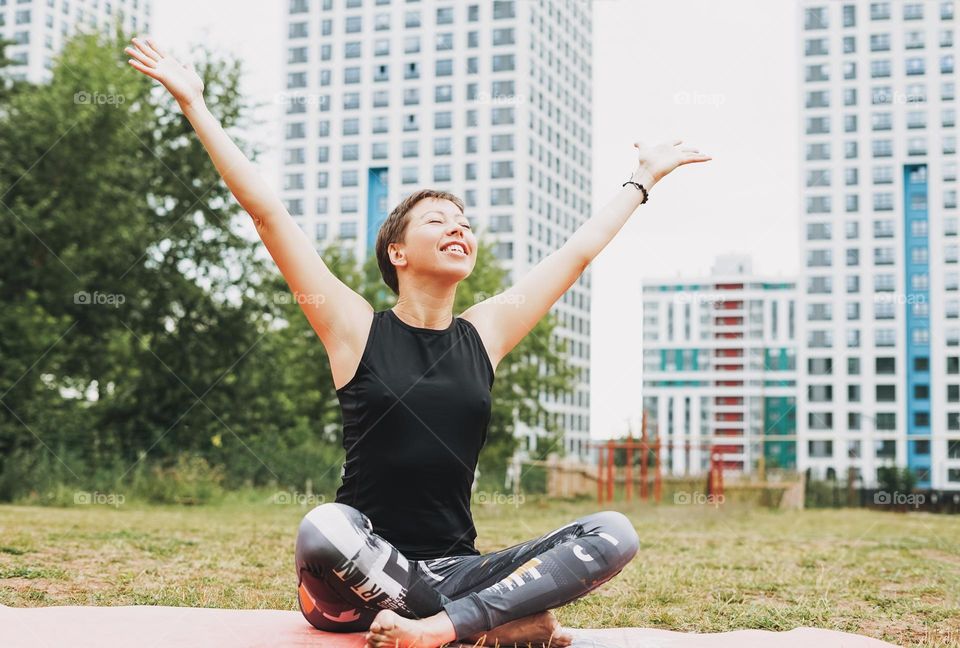 Young smiling woman practice yoga outdoors in city. New normal social distance. Physical and mental health