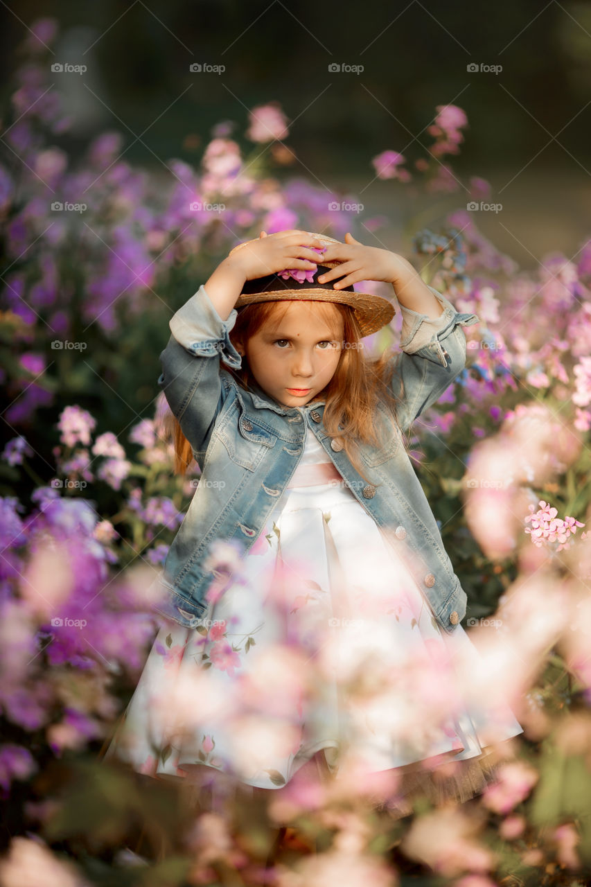 Cute little girl portrait in blossom meadow at sunset 