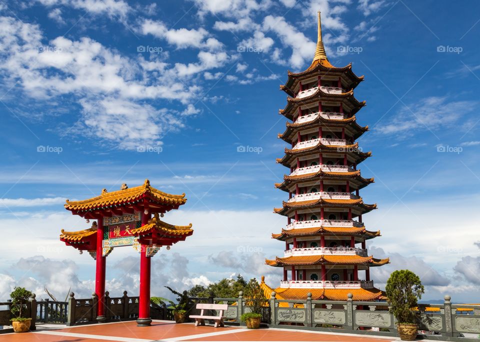 Chinese gate and pagoda. Chinese red gate and tall pagoda photographed against blue sky with few clouds