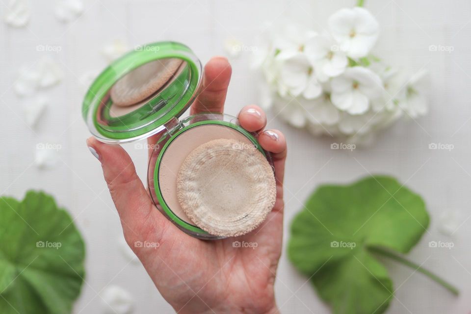 Lady's hand is holding a case with a makeup powder