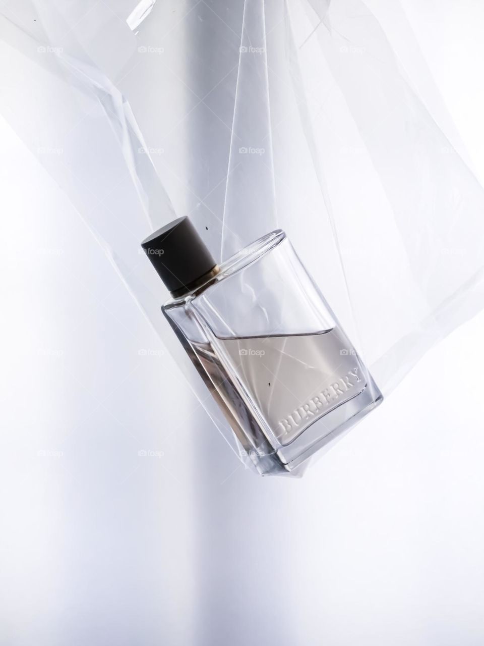 A perfume bottle in a clear plastic bag with white background 