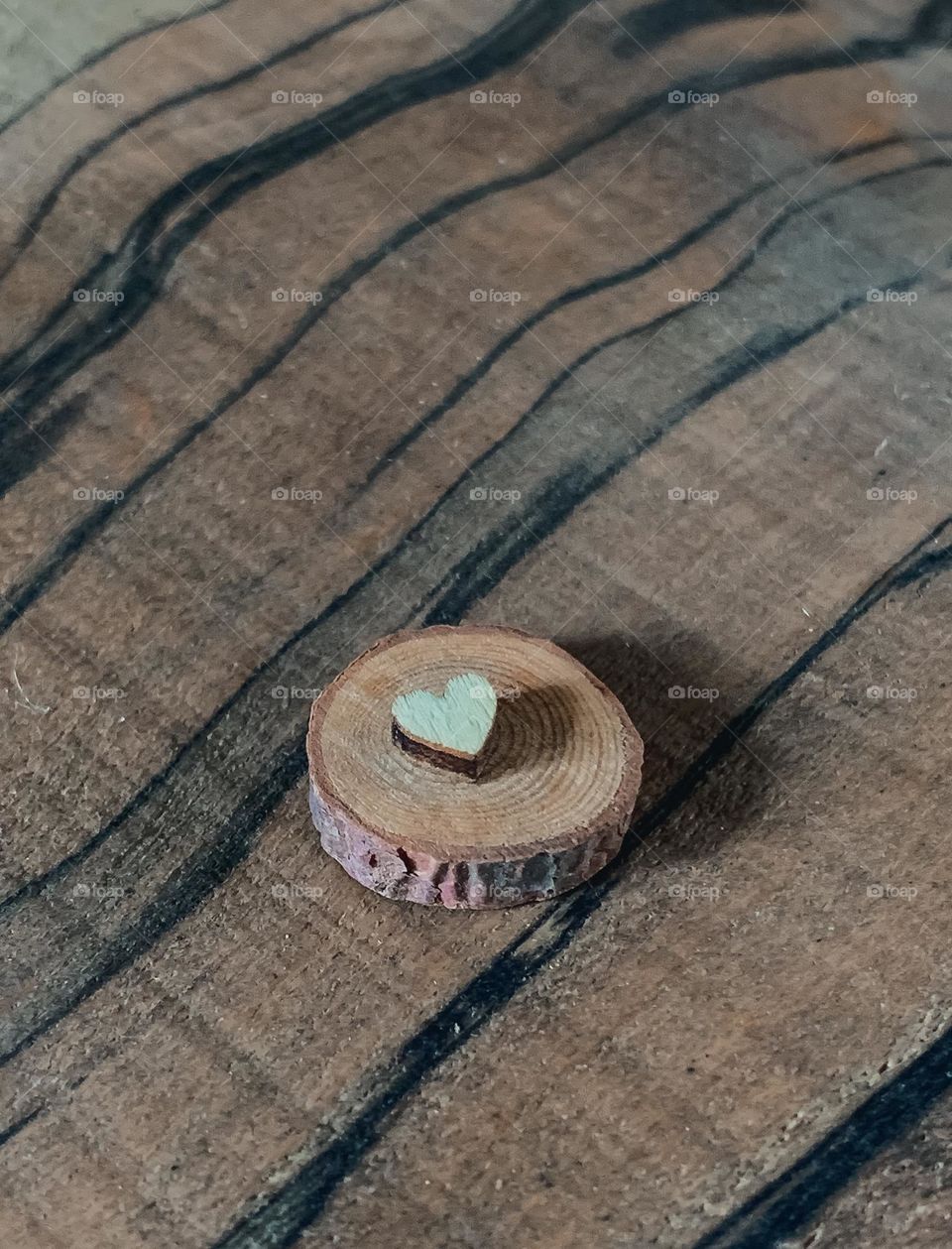 A wooden heart, on a wood cookie against a wooden background 