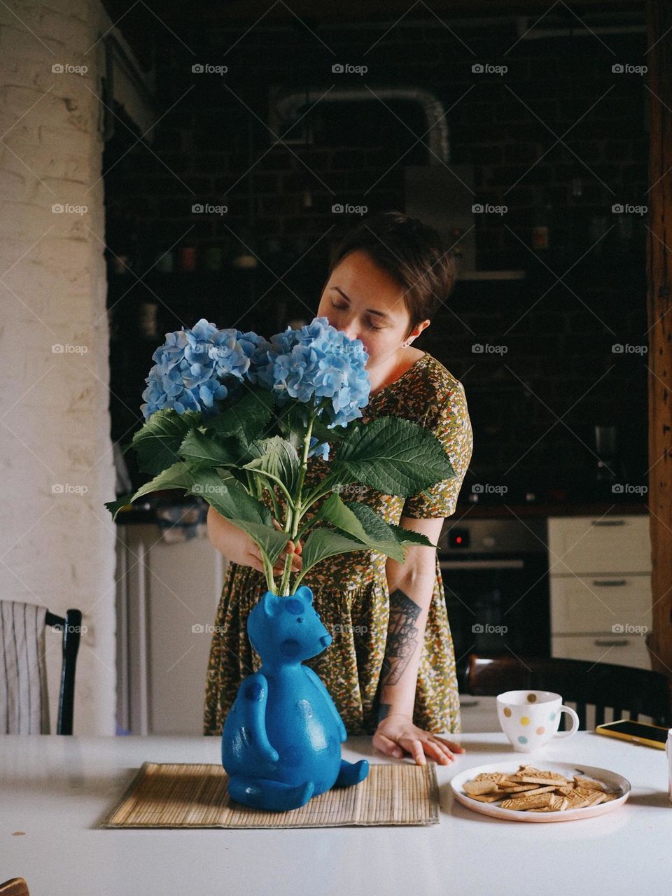 Young beautiful woman with blue hydrangea in cozy home, portrait of woman 