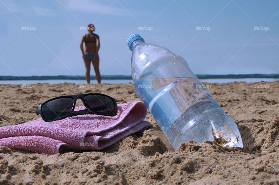 Bottle with clean drinking water lies on the beach