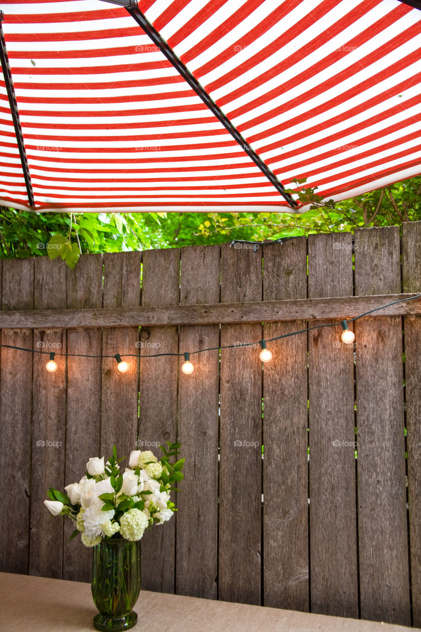 A white bouquet under a red and white umbrella with outdoor lights