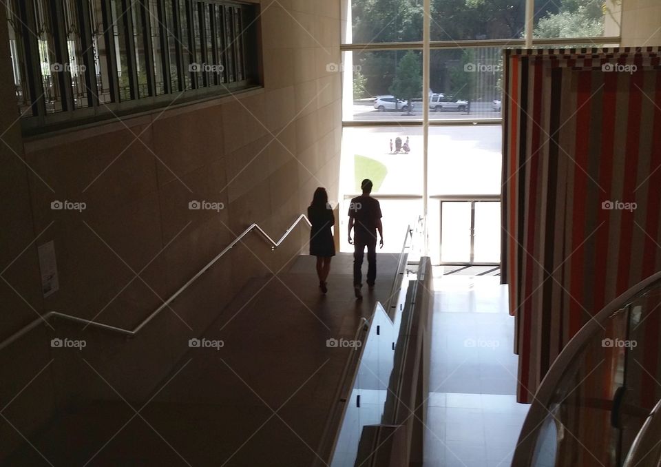 A man and a woman walking in an urban building from a to b