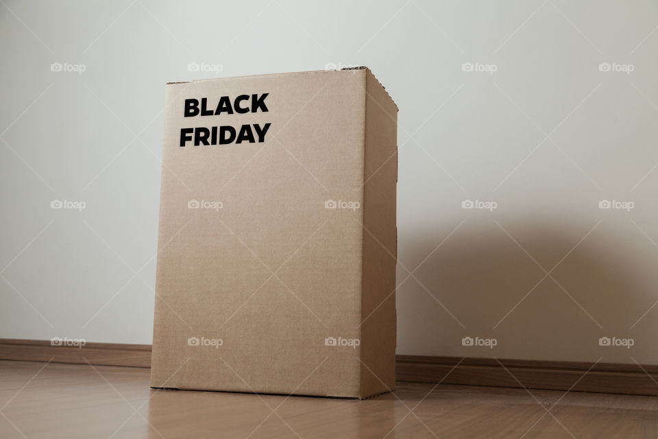 Cardboard box with black friday order written on the box placed on the floor in an empty room with a neutral background. delivery concept. economy concept. black friday concept. shopping concept.
