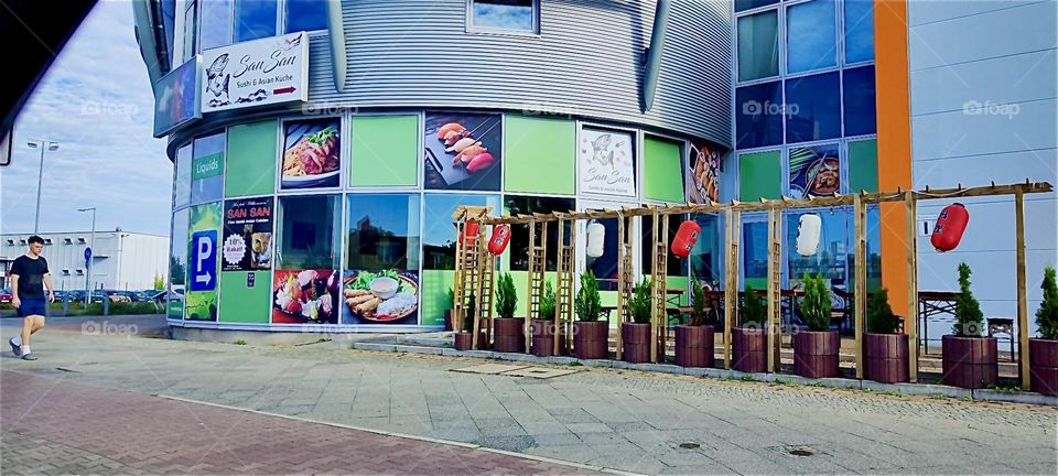 These are impressions from the road out of “Berlin”, Germany in the district of “Spandau” on the way to the “Baltic Sea” or “Ostsee”. We are passing by the sushi restaurant “San San” with colorful photos and panels. 2024. Hypnotic Productions