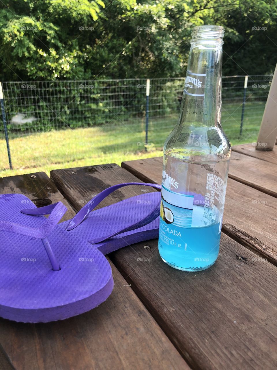 A cool blue drink on deck along with purple flip flops. 