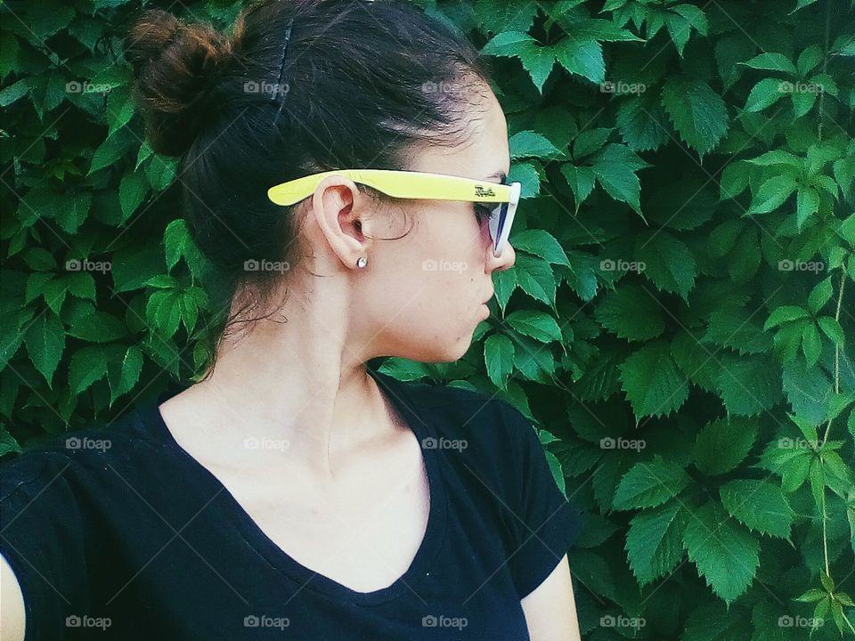 portrait of a girl with glasses on a background of foliage