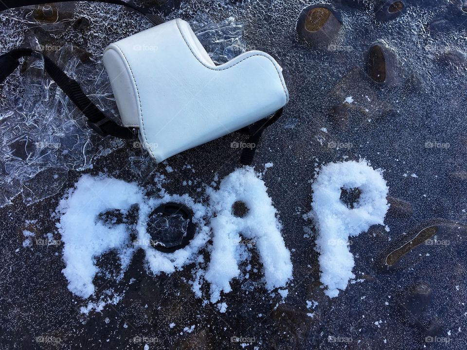 White snow spelling FOAP on frozen river water 