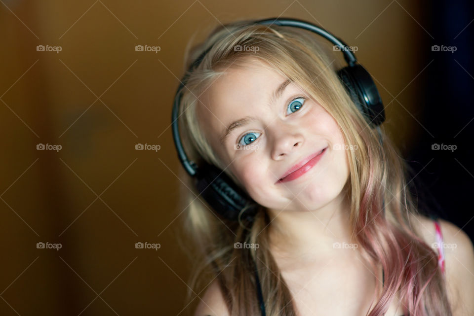 Cute kid girl listening music in stereo headset