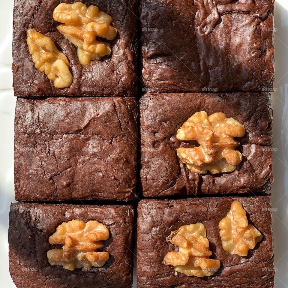 Plain original brownies and walnut brownies put together on white glass plate close up shot 
