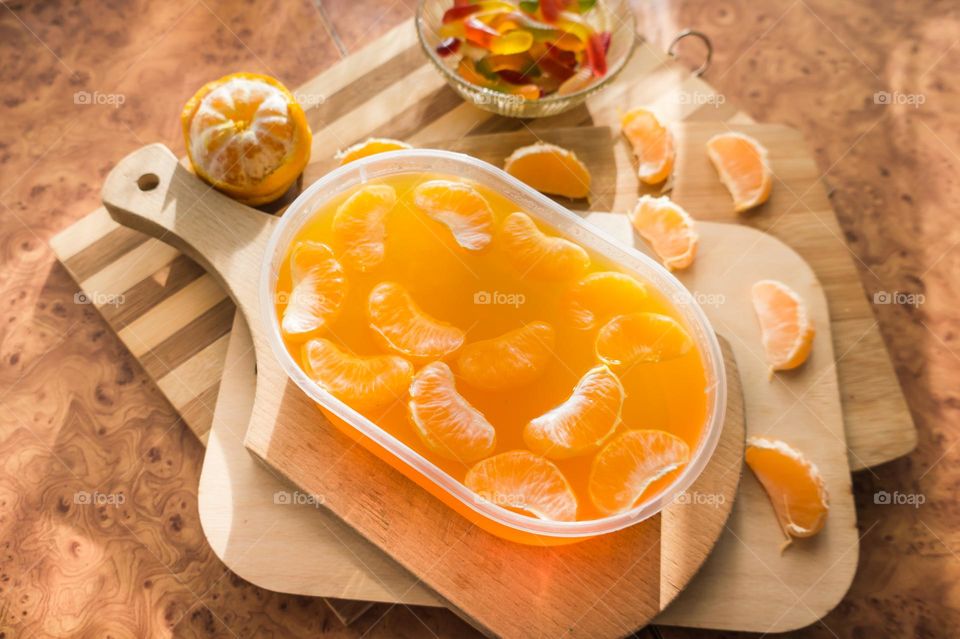 Delicious orange jelly with tangerine slices in a container and jelly worms.