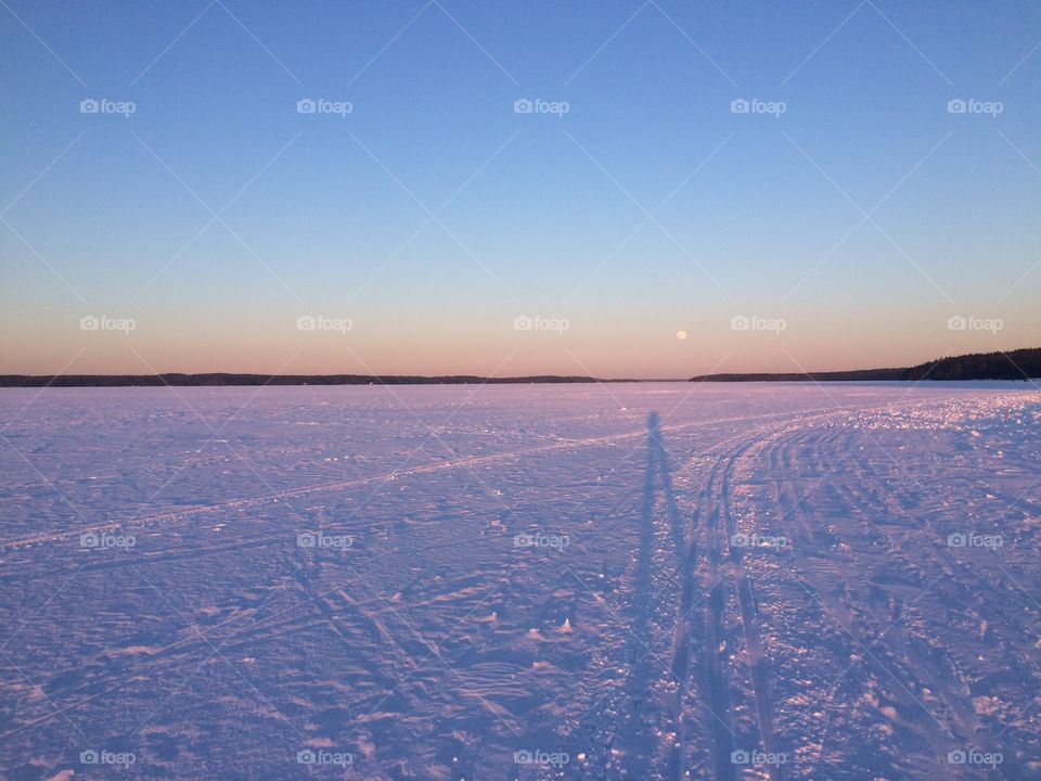 The moon in the horizon in the Sunset on a Frozen lake 