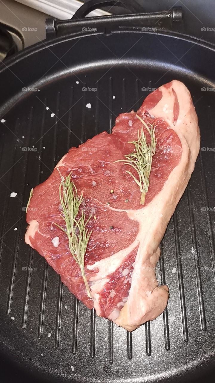 Fresh beef steak ready to cook with rosemary and butter
