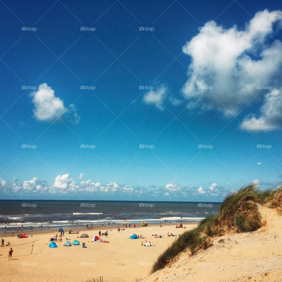 Lovely summer day at the sea. Beach and sea and dunes, people on the beach, enjoying the sunny day