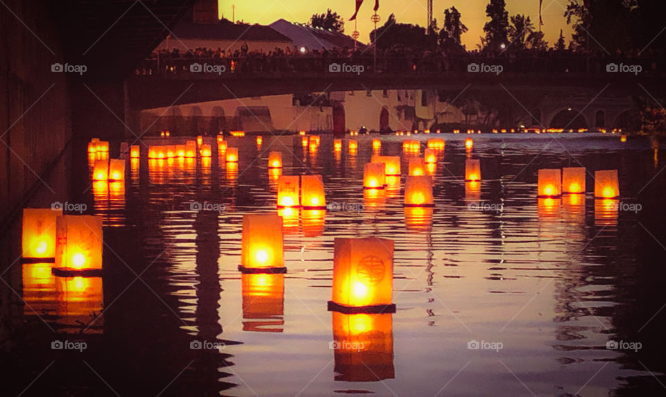 Crowds of people on the bridge watch hundreds of candle lit lanterns float down the Rio Nabão - Tomar - Portugal 2019