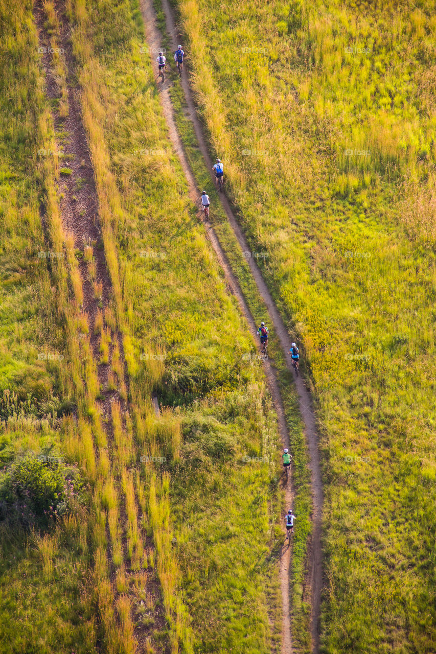On the move - cycling outdoors is the best to stay fit and healthy! Image from bird's eye view above cyclists riding mountain bikes outdoors on path