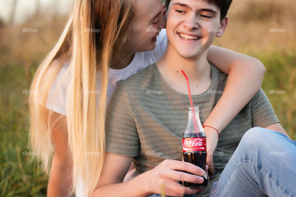 Close-up of a happy teenage couple holding cold drink in hand