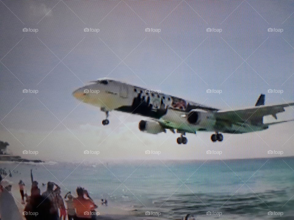 plane preparing for its landing landing near the beach above the tourists very exciting