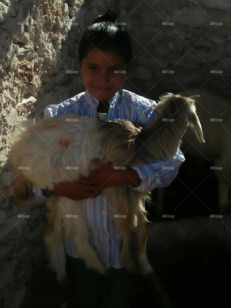 A beautiful girl holding a  goat.