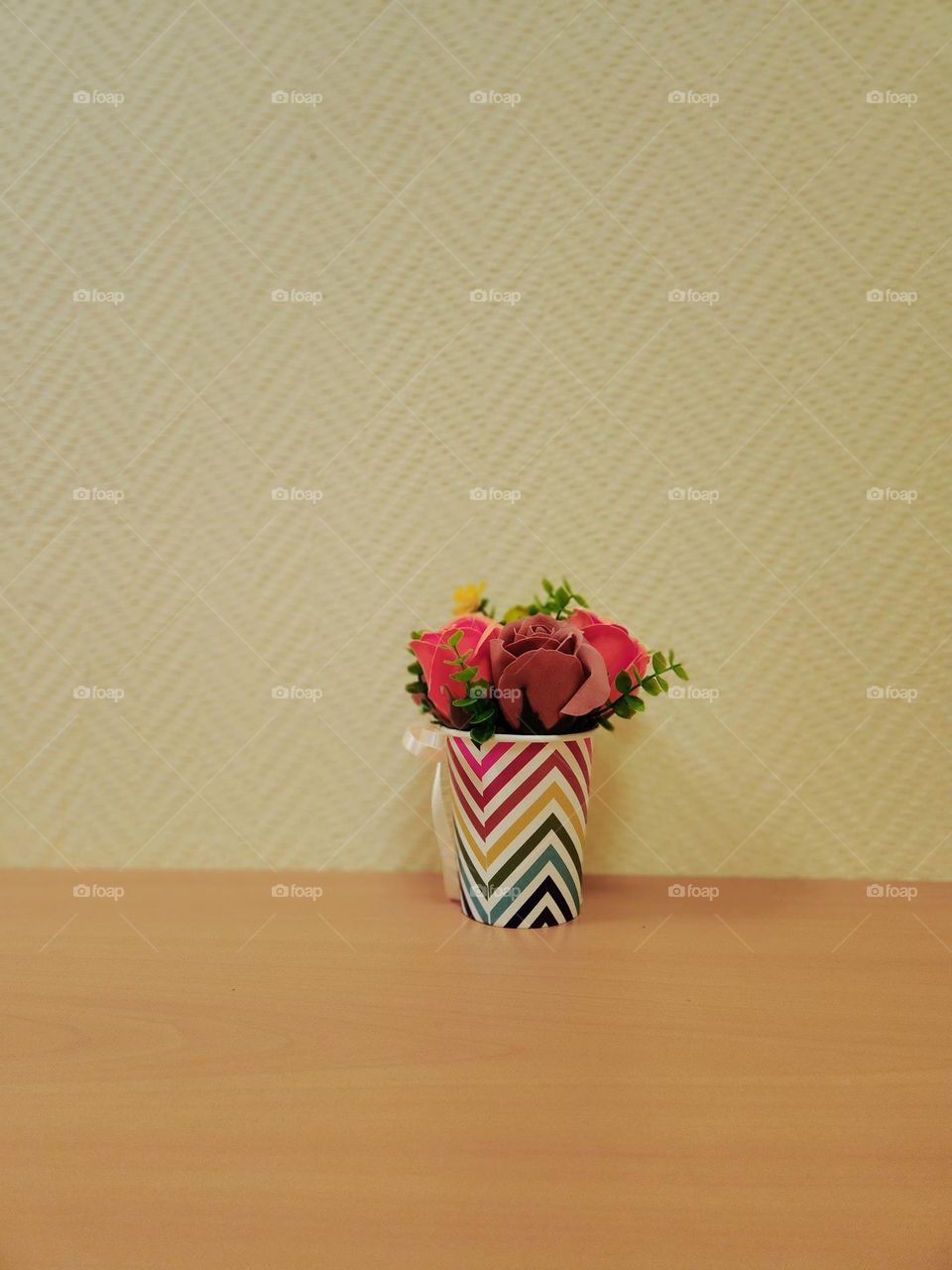 Flowers in a paper vase against a yellow background