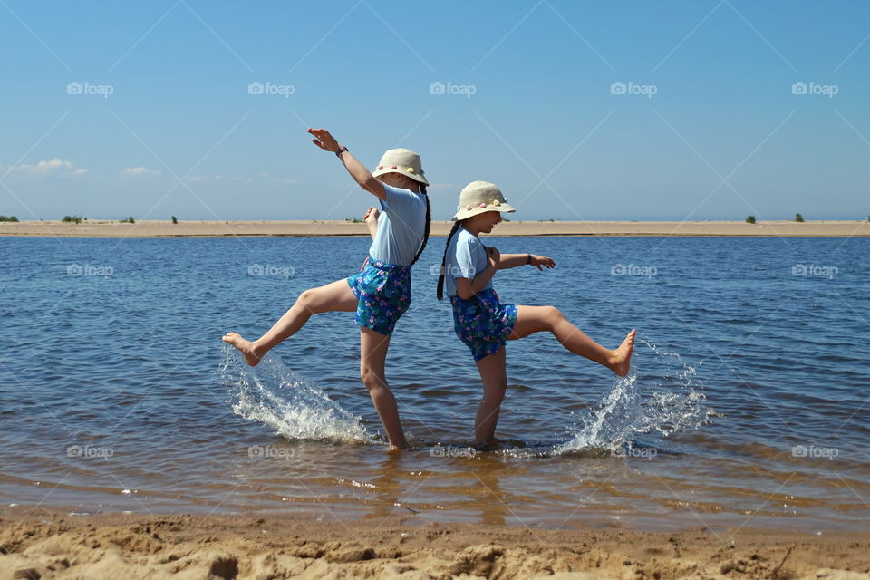 Two children splash in the water by the sea