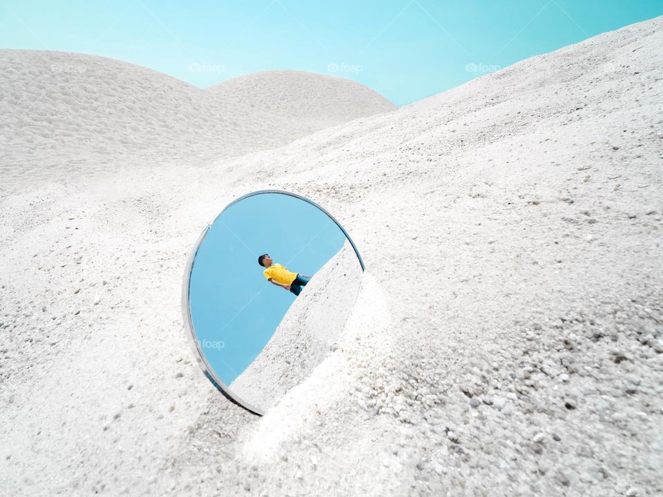 A boy in a mirror reflection by the beach