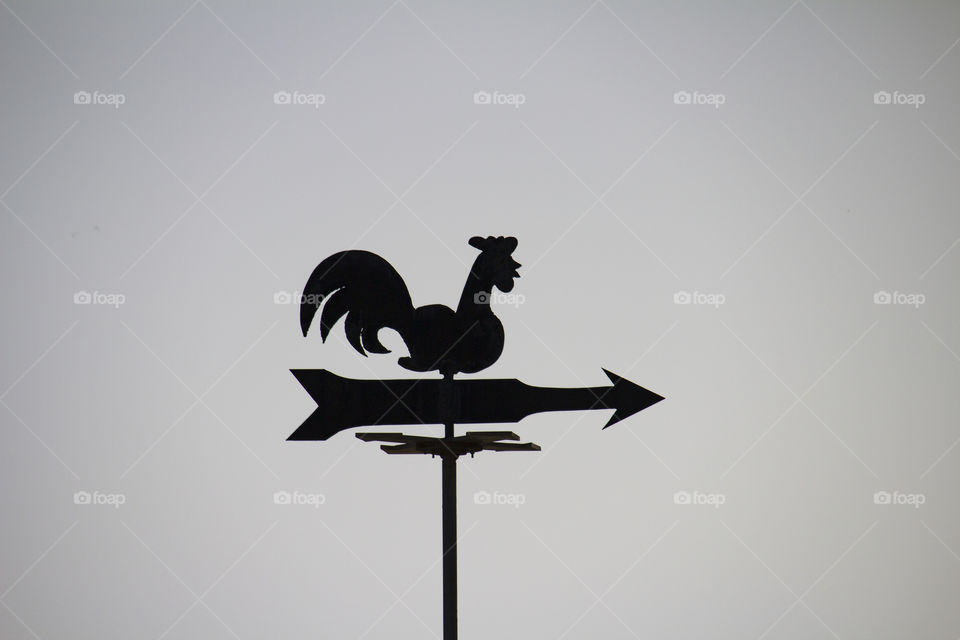wind direction.  weather vane on a grey sky