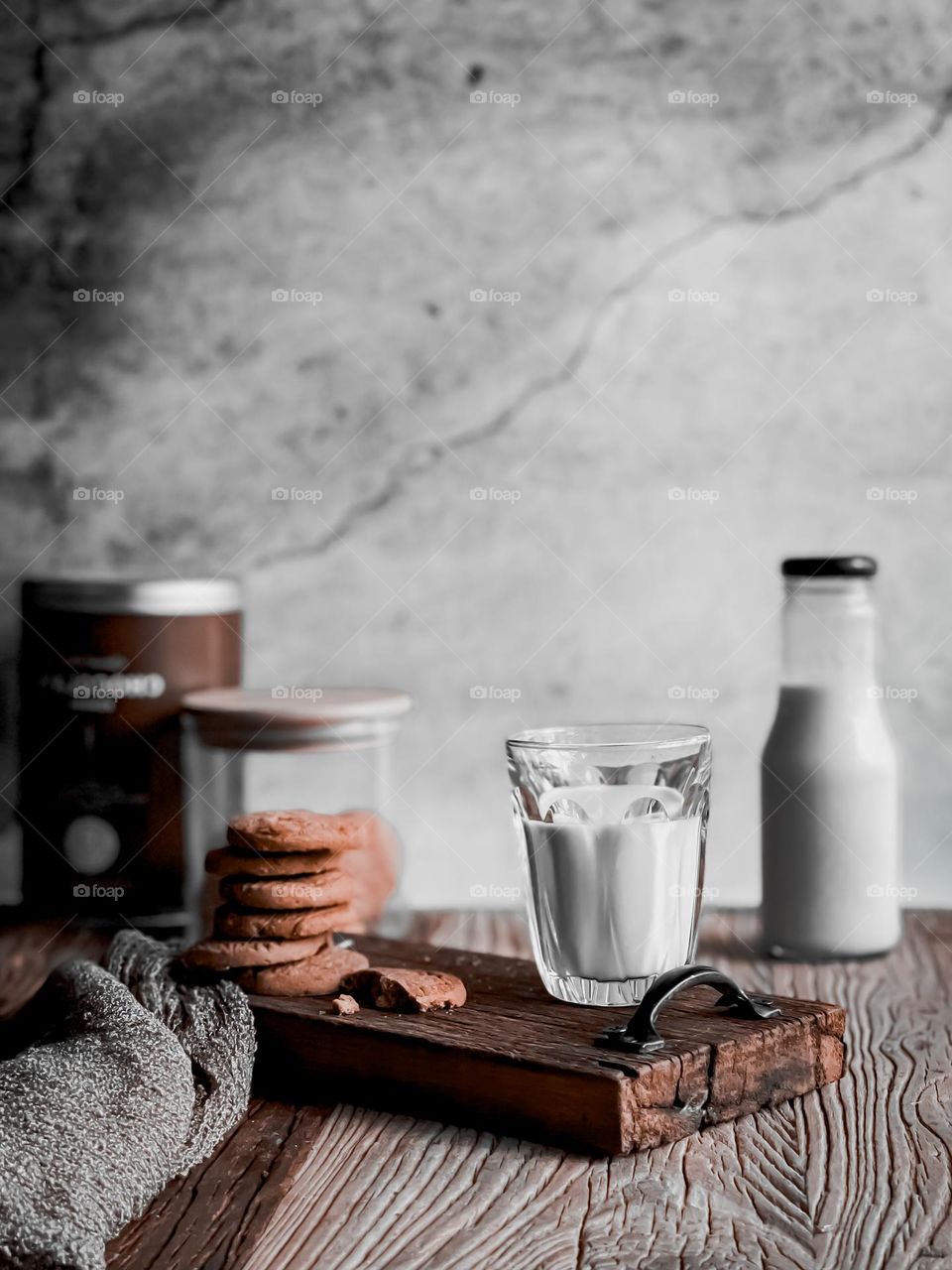 Breakfast with a cup of milk and cookies. A bottle of milk at the back and biscuits jar