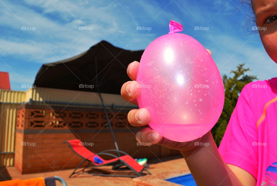 Child about to toss balloon. Water filled balloon, pink!