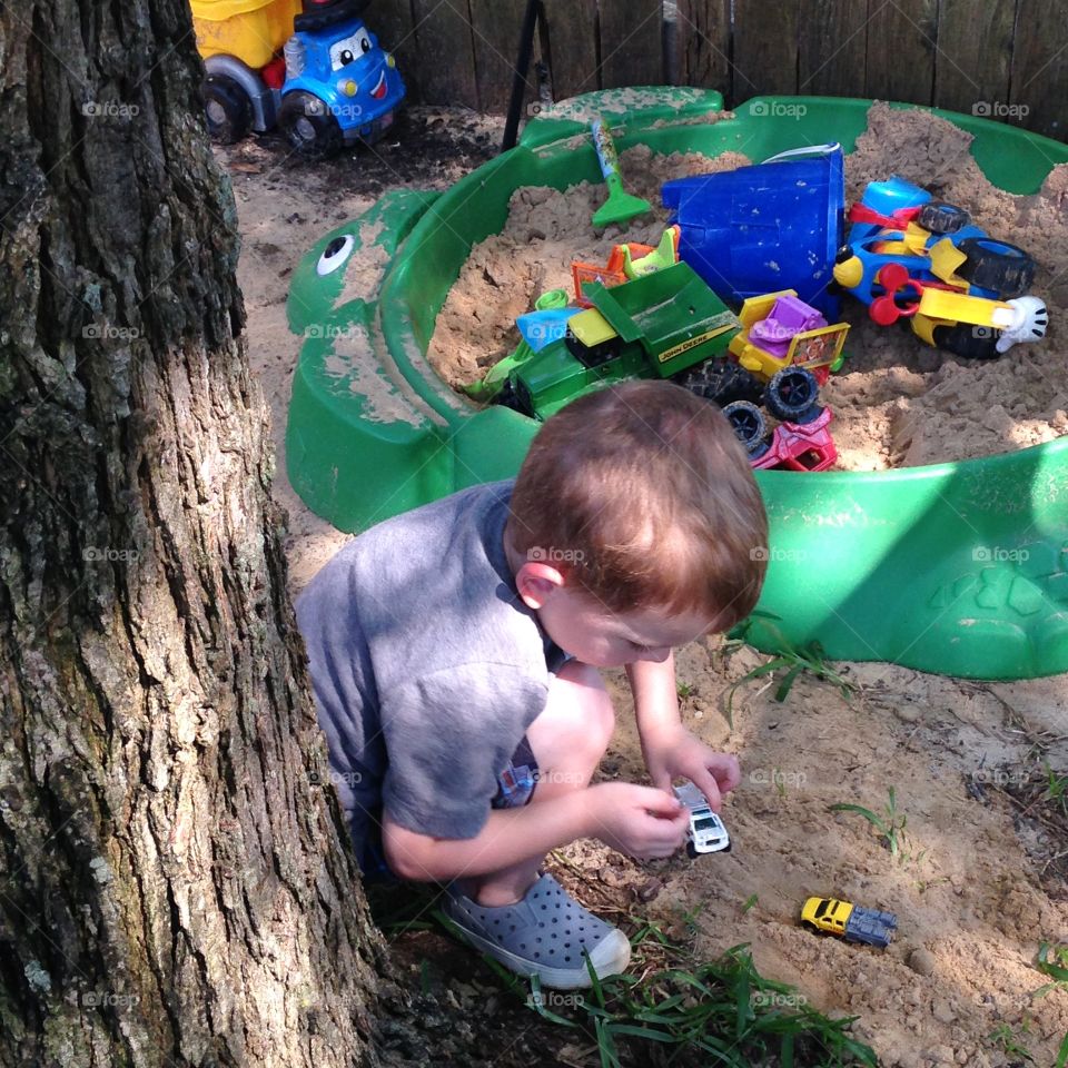Boy toys . Little boy playing with hot wheels and sandbox