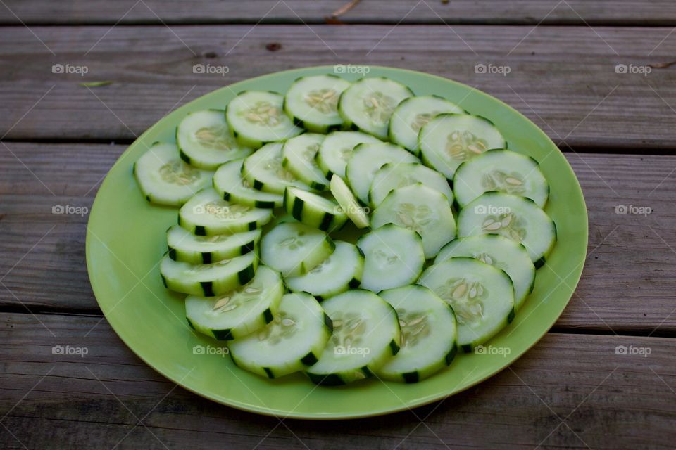 Fruits! - Cucumbers in a spiral pattern on a green plate on a wooden background