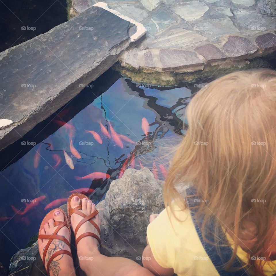 Mother and daughter feeding goldfish