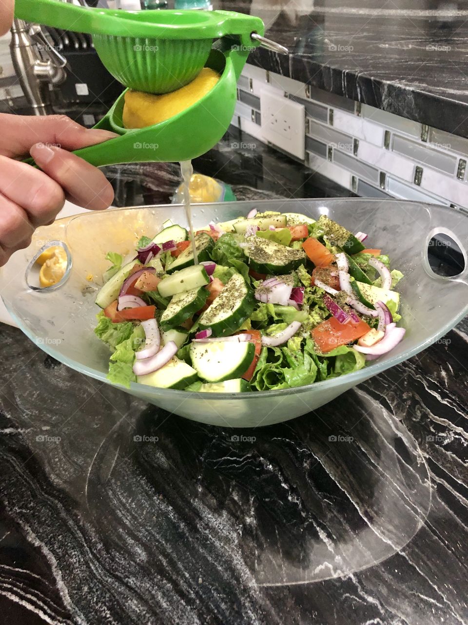 Squeezing lemon on fresh salad 