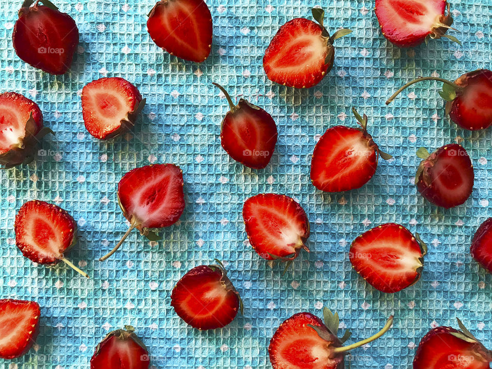 Slices of red ripe strawberries on blue textile background 