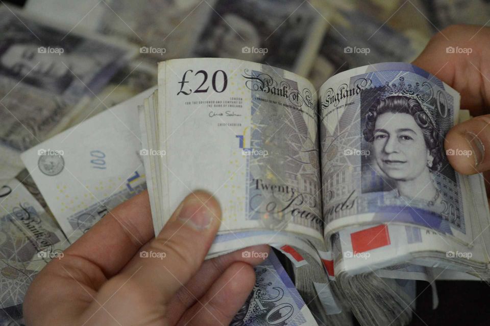 Human's hand holding British currency