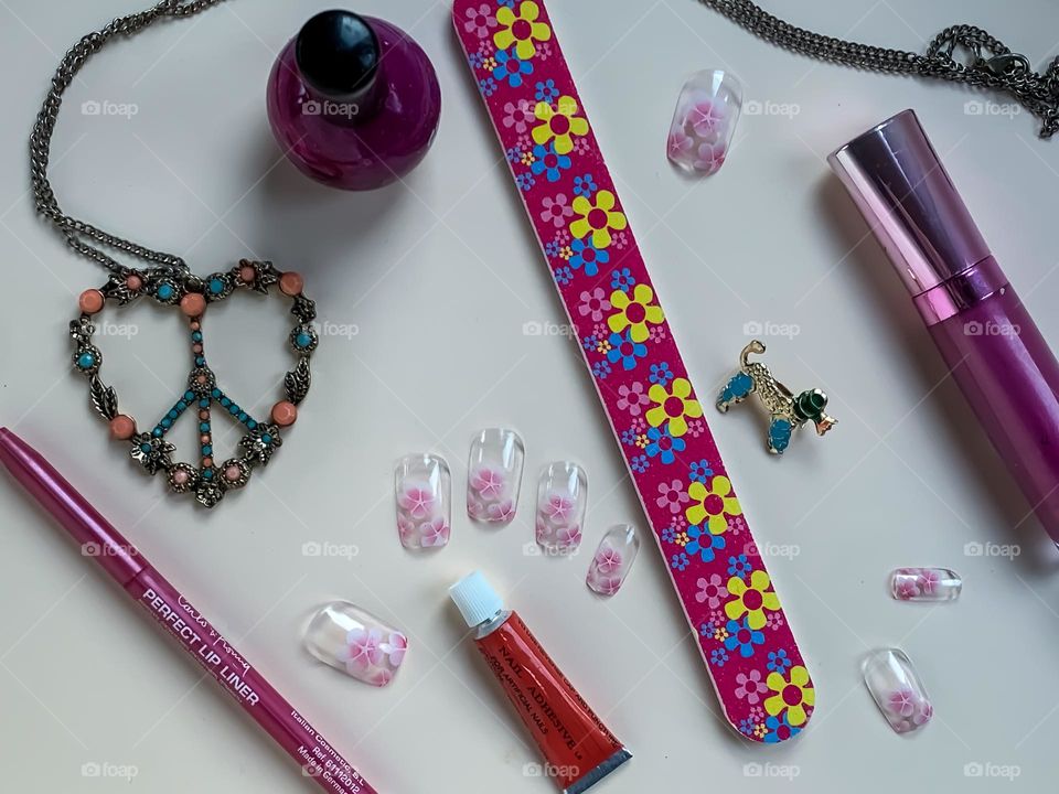 Flat lay of assorted cosmetics and jewellery featuring false nails