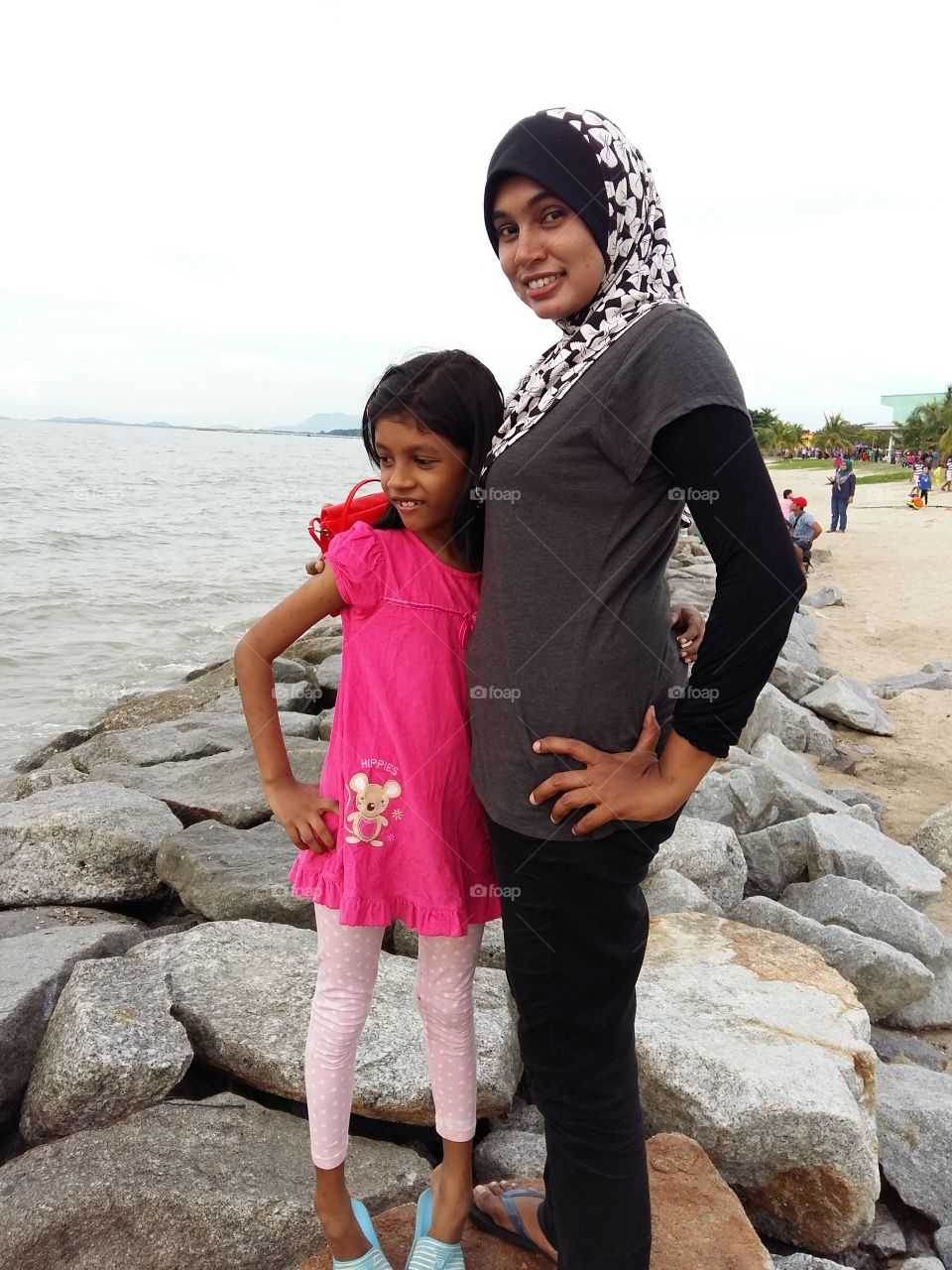 Two siblings standing on rock near the sea