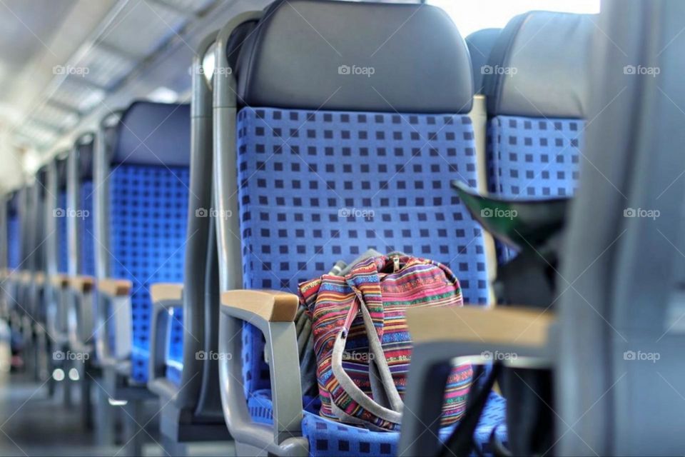 A colorful bag lies on a seat in an empty train compartment