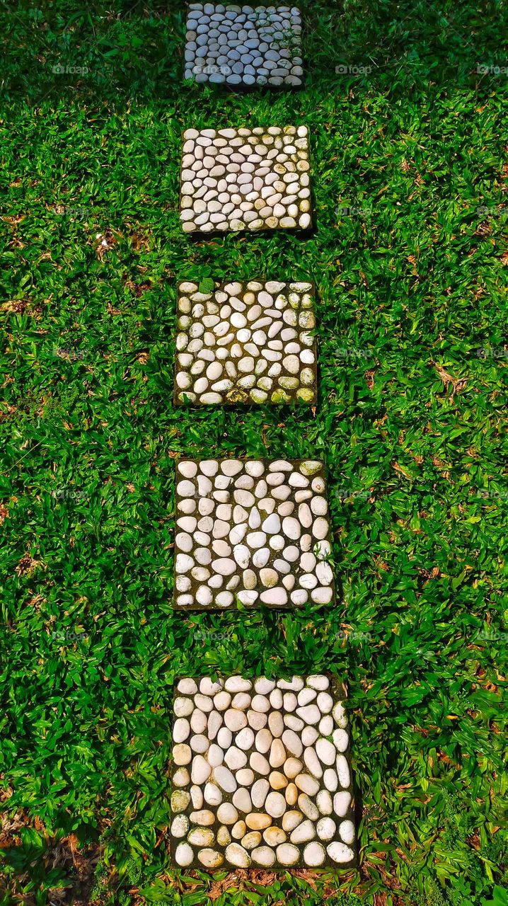 Square stepping stone used pathway on the grass at home garden or park.