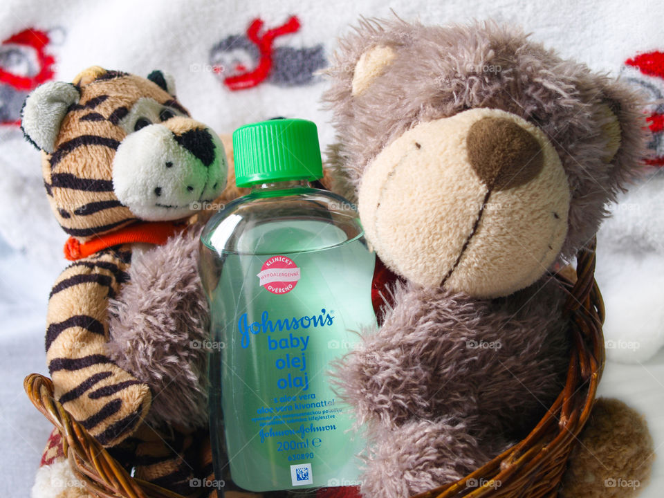 Plush toys in a wooden basket, Johnson's Baby oil in the middle.