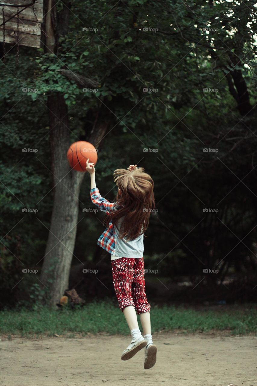 Child playing basketball in the yard