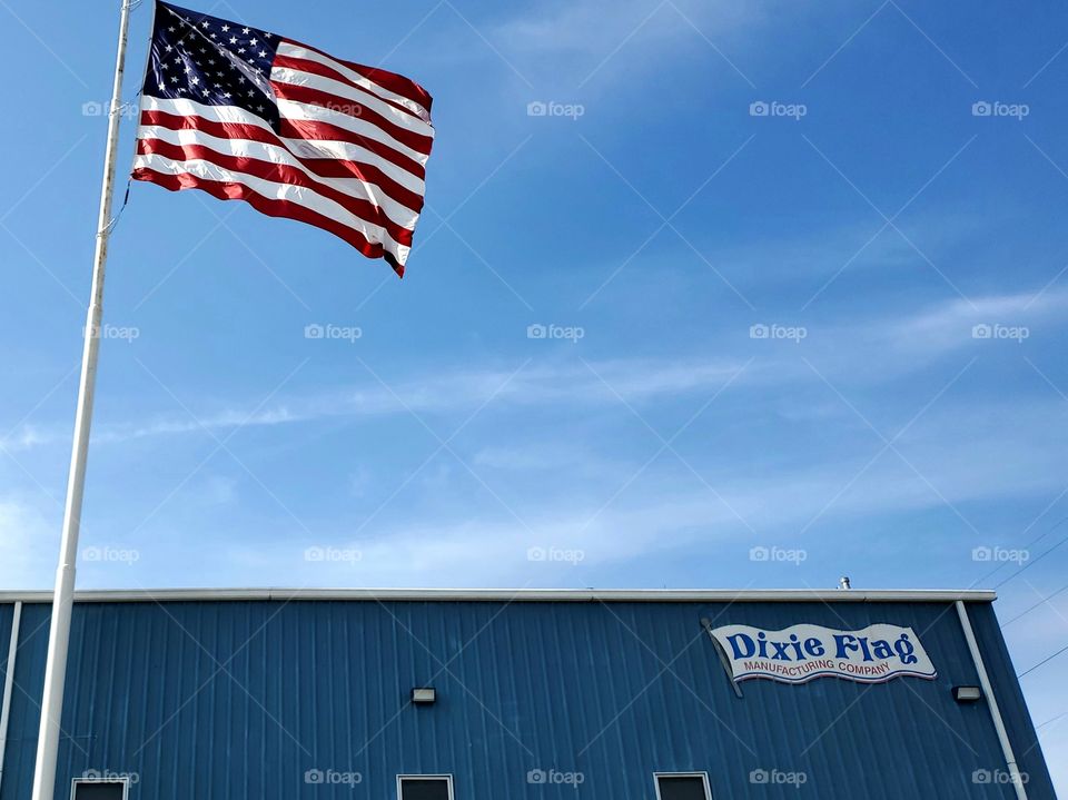 Established originally in 1958 the Dixie flag company flying a large American flag on a bright and sunny blue sky day. This company has manufactured the flags for many recognized events and places, including four presidential inaugurations.