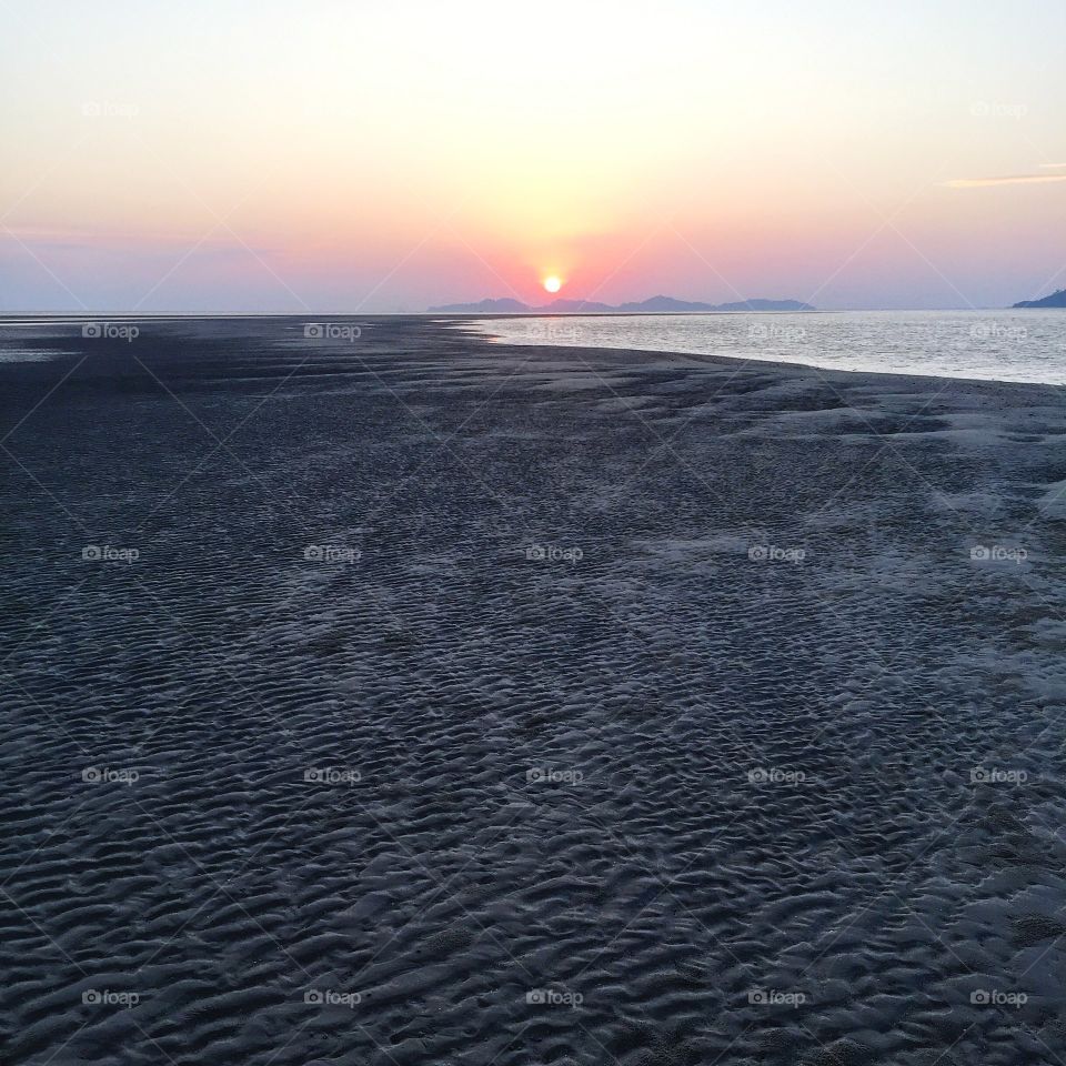 Scenic view of sandy beach against sunset sky